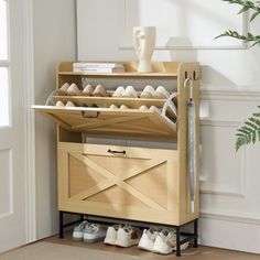 a wooden shoe rack with several pairs of shoes in it next to a potted plant