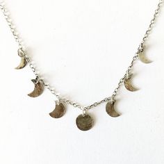 "Silver moon phase necklace.  This delicate necklace is made from 7 small hammered silver pendants to represent the phases of the moon.   The central full moon pendant measures approximately 0.8cm.  The necklace is on a short sterling silver cable chain that measures 15\" long so that it is a short choker style.  2\" of Additional links have been added to the end of the chain so there is  room for adjustment in the length. If you would like this necklace made on a longer chain please request a c Sterling Silver Half Moon Charm Necklace, Sterling Silver Moon Phase Charm Necklace, Adjustable Sterling Silver Moon Phase Necklace, Moon Phase Jewelry, The Phases Of The Moon, Moon Phases Necklace, Phases Of The Moon, Celestial Necklace, Coin Pendant Necklace