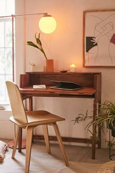 a desk with a chair, lamp and pictures on the wall in front of it