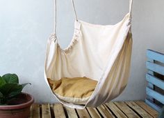 a hammock chair hanging from a rope on top of a wooden table next to a potted plant