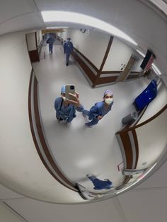 two doctors in scrubs are walking through the hospital corridor, looking at their cell phones