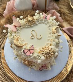 a heart shaped cake with butterflies and flowers around it on a plate in the middle of a table