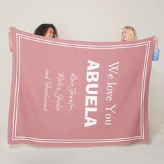 two women holding up a pink towel with the words, we love you written on it