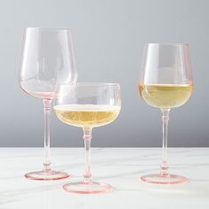 three wine glasses sitting on top of a white counter