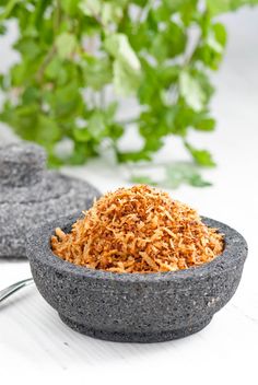 a bowl filled with some kind of food on top of a white table next to a potted plant