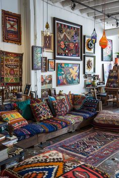 a room filled with lots of colorful rugs and pictures on the wall above them