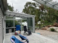 two lawn chairs sitting on top of a cement floor next to a building with glass doors