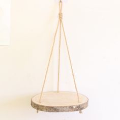 a wooden swing hanging from a rope on a wall