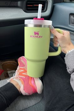 a person sitting in the back seat of a car holding a cup with a straw