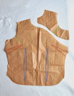 a piece of brown paper with blue and red lines on it, cut out to look like a man's torso