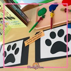 there is a dog paw cut out on the table next to some markers and pencils