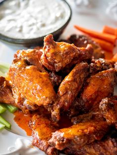 chicken wings with carrots and celery on a white plate next to dip