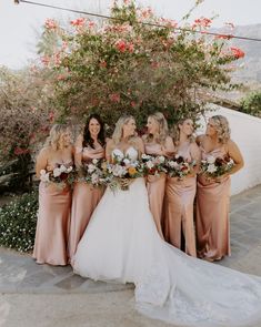 a group of women standing next to each other in front of a flower covered tree