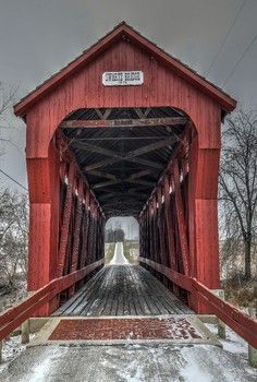 a red covered bridge with snow on the ground