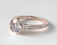 a white gold engagement ring with diamonds on the sides and a round diamond in the center