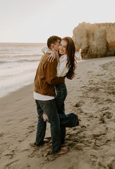 a man and woman embracing on the beach