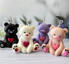 four different colored teddy bears sitting next to each other with hearts on their paws and eyes