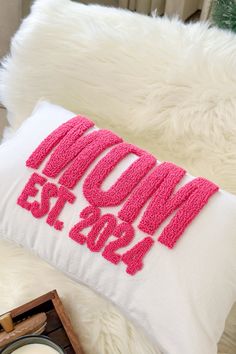 a pillow that says mom est 2013 on it next to a candle and other items