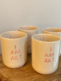 four coffee cups with writing on them sitting on a table