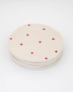 four white coasters with red hearts on them sitting side by side against a white background