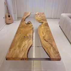 a table made out of wood and metal in a room with white walls, two couches and a guitar on the floor