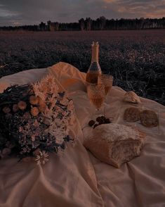 a table topped with bread, crackers and wine on top of a white cloth