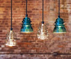 three glass pendant lights hanging from a brick wall