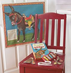 a red wooden chair sitting next to a painting on the wall