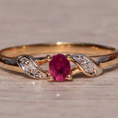 a close up of a ring with a red stone in it on a wooden surface