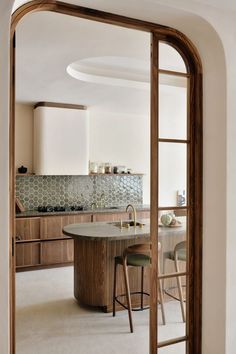 an open door leading to a kitchen with wooden cabinets and counter tops in the center