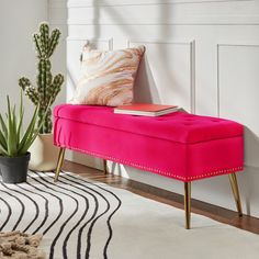 a pink bench sitting on top of a white rug next to a potted plant