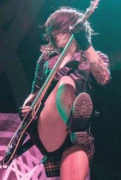 a woman in tights holding a guitar on stage