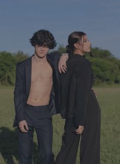 two people standing next to each other in a field