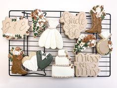 wedding cookies on a wire rack with flowers and bride's dress cookie toppers