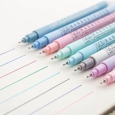 several different colored pens lined up on top of each other in an open notepad