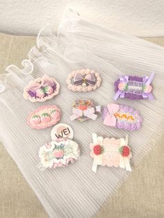 several different types of hair clips on top of a white cloth covered bag with ribbon