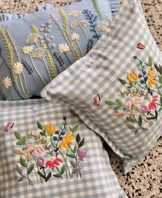 three pillows with flowers on them sitting on the floor