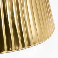 a gold pleated lamp shade on a white background