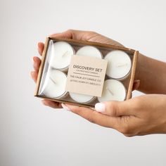 a person holding a box filled with white candles