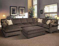 a large sectional couch in a living room with lots of pillows on top of it