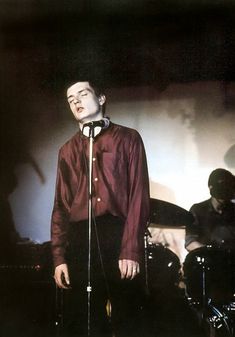 a man standing in front of a microphone with his eyes closed and hands behind him