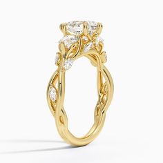 a yellow gold engagement ring with three stones on the side and an intricate vine design