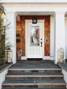 a white front door with two lit candles on the steps next to it and an entry way