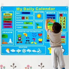 a young boy standing in front of a blue calendar