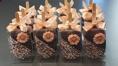 four chocolate covered candies with flowers and wooden sticks in clear boxes on a table