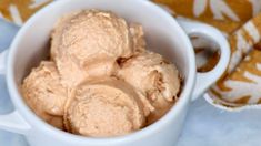 a white cup filled with ice cream on top of a table next to a blanket