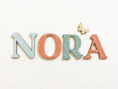 the word nora is made up of wooden letters with butterflies on top of it