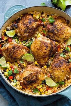 chicken and rice in a skillet with limes, corn, and cilantro