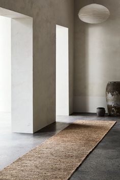 an empty room with two vases and a rug on the floor