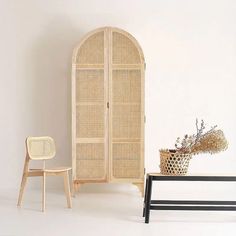 a white room with a chair, cabinet and vase on the floor next to it